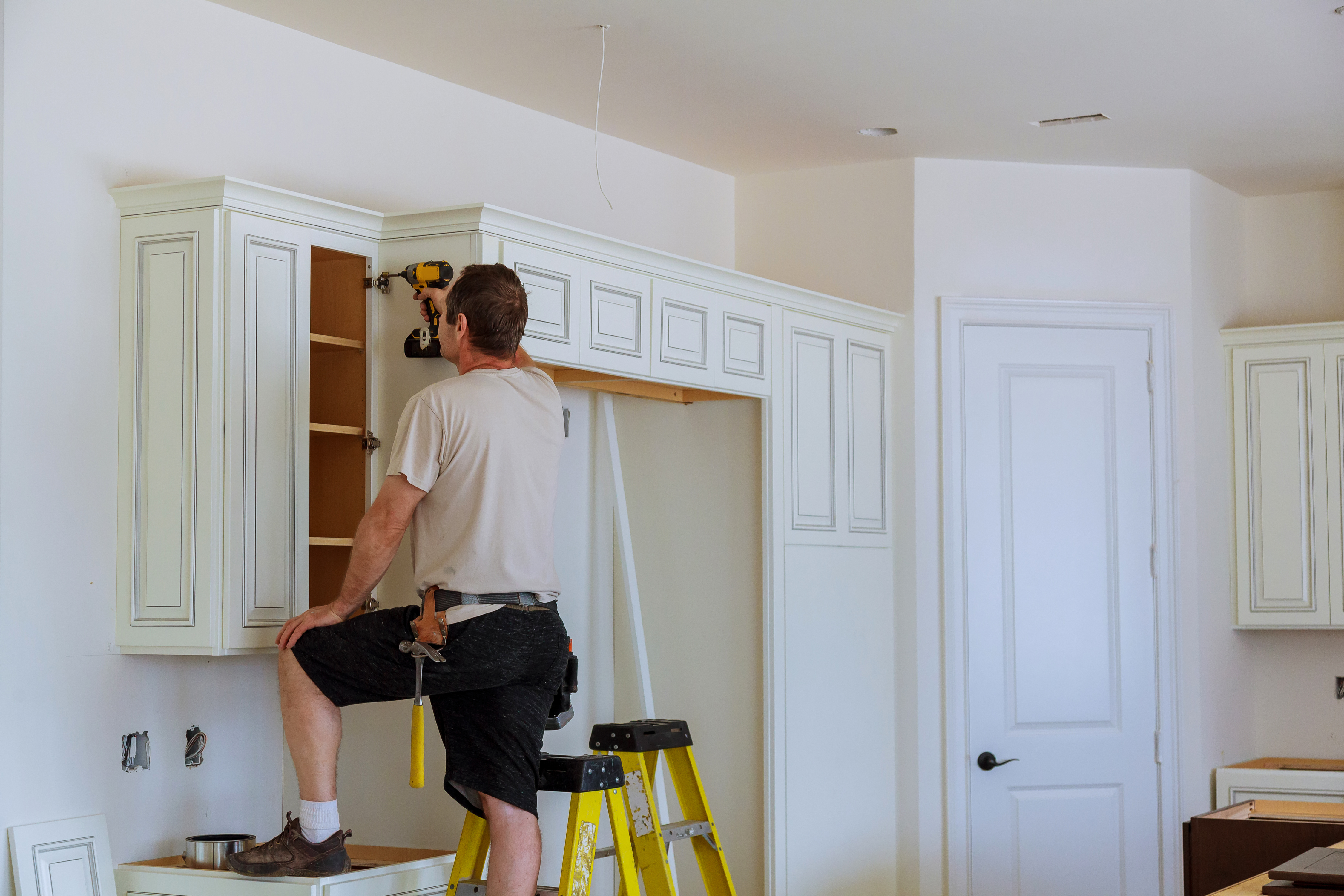 Worker installs doors to kitchen cabinet. Installation of doors on kitchen cabinets